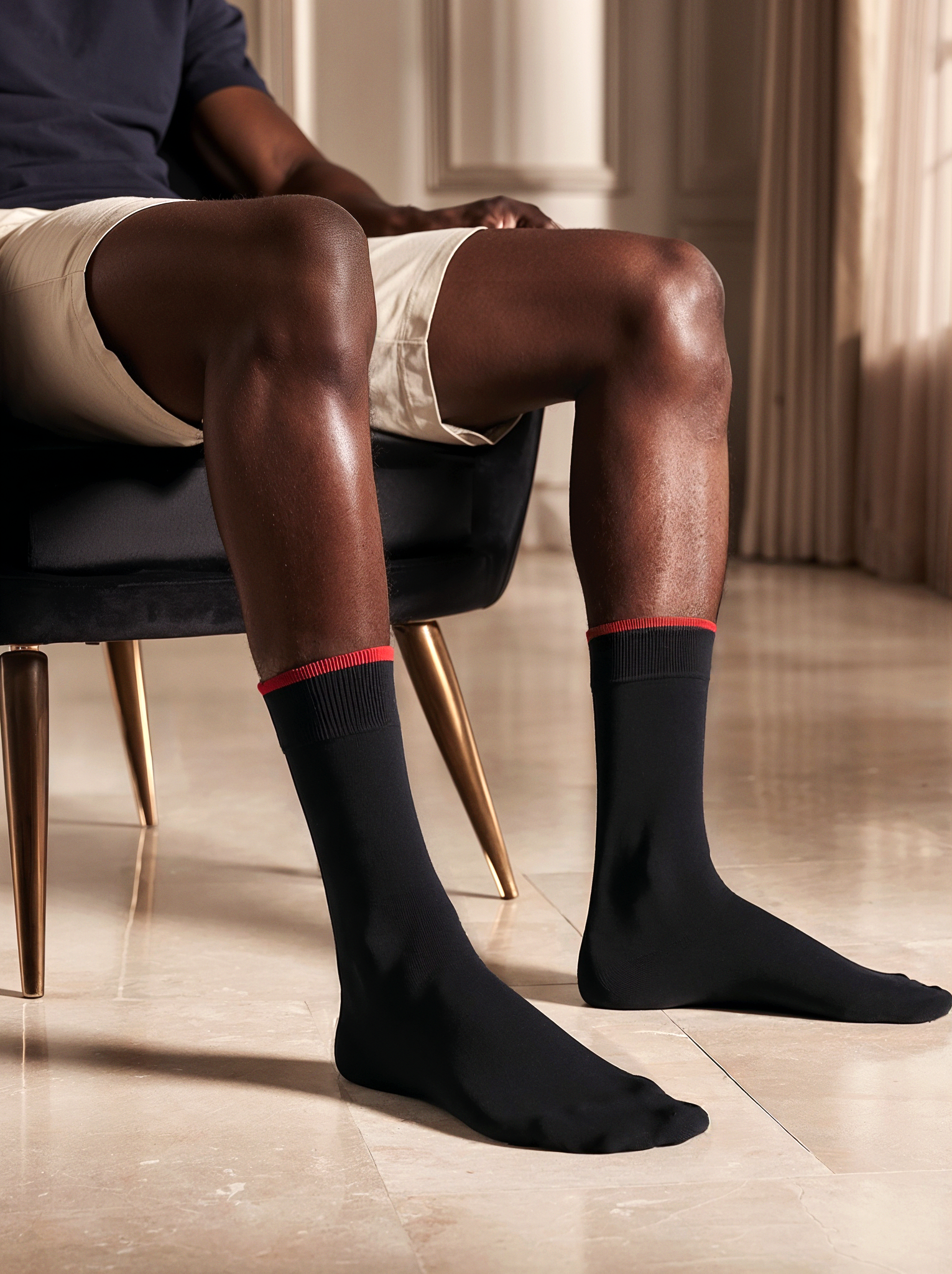 Person wearing black bamboo socks BAMLUGA with red trim sitting on a chair indoors.